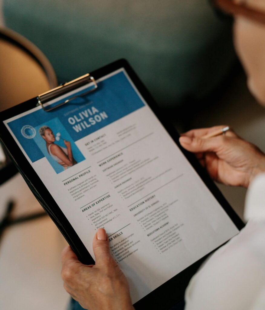 lady holding clip board with resume that has a photo and the name Olivia Wilson