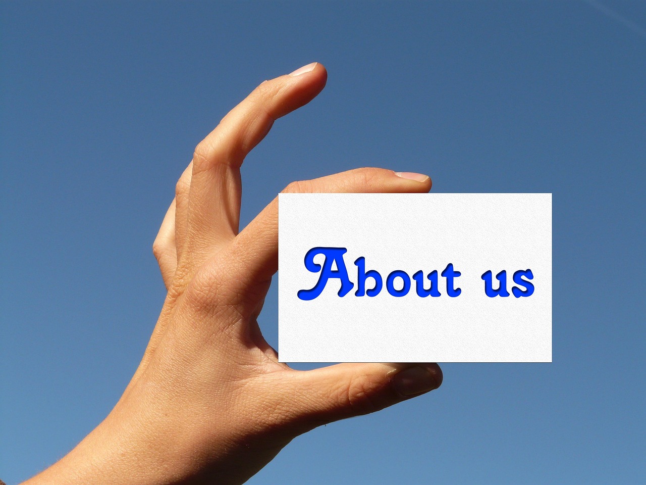 Hand holding a business card that say About Us in blue font.